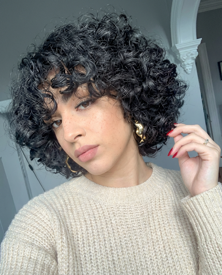 Side portrait of woman with voluminous curly bob and tousled fringe wearing gold hoops generated by blondefilter.net