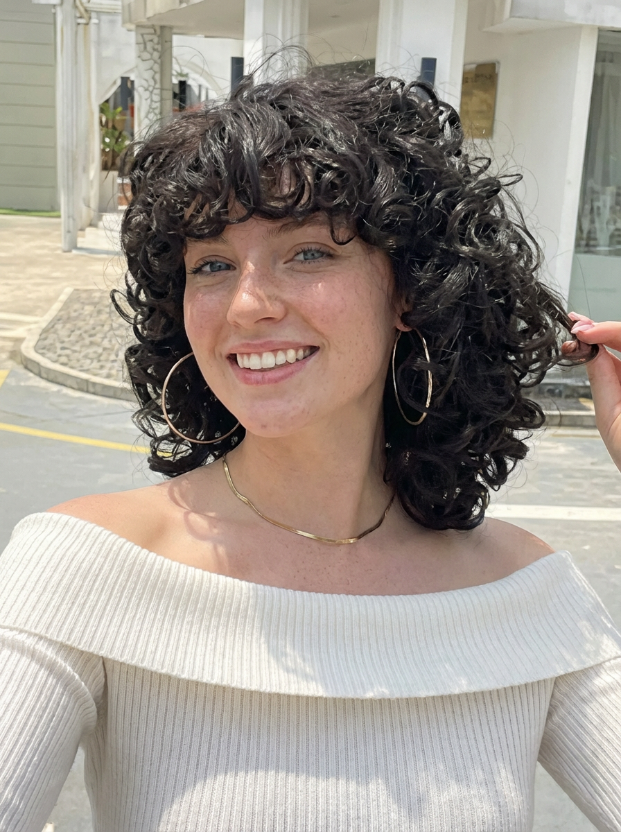 Outdoor portrait of smiling woman wearing loose curly afro hairstyle with bangs and hoop earrings generated by blondefilter.net